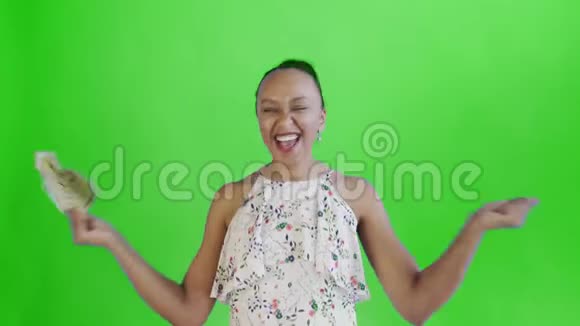 满意高兴兴奋非洲裔美国妇女显示金钱并说YEAH在绿色背景白色连衣裙视频的预览图