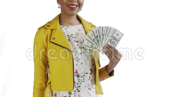 美国黑人妇女在工作室的白色背景上带着钱迷的肖像黄色夹克视频的预览图