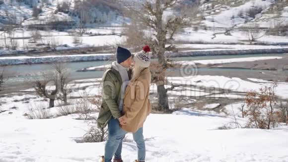 年轻夫妇抱着美丽的雪山在背景上视频的预览图