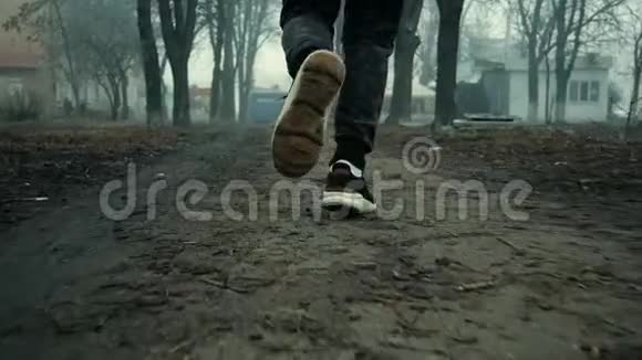 在寒冷的雾天早晨在城市公园里奔跑的男运动员腿的特写镜头视频的预览图