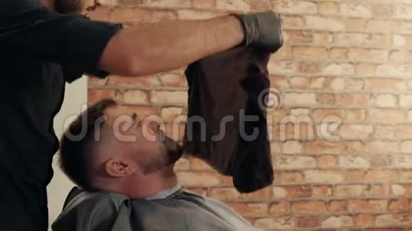 理发店在理发前把热毛巾放在男性脸上男性造型师使用湿毛巾胡须男视频的预览图