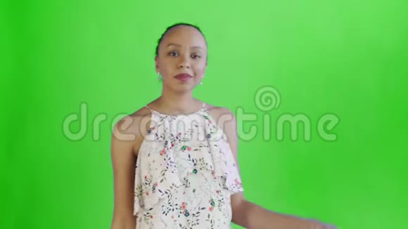 美国黑人妇女带着钱迷正在工作室的绿色背景上显示拇指带花的白色裙子视频的预览图