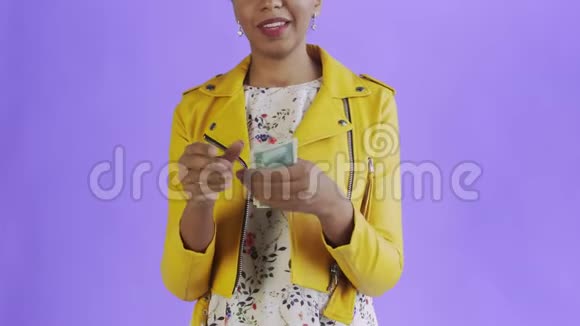 一位迷人的美国黑人妇女正对着一件紫底黄夹克数钱视频的预览图