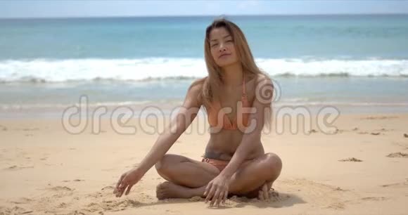 快乐的女人坐在沙滩上视频的预览图