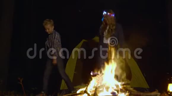 晚上在篝火旁跳舞的可爱快乐的青少年视频的预览图