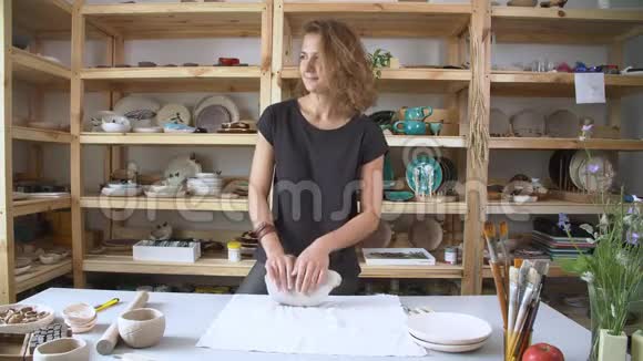 年轻女子在一家时尚的陶瓷工作室工作一个小女孩手里拿着一个陶土块揉着陶土视频的预览图