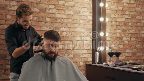 年轻美发师与帅哥客户聊天剪头发视频的预览图