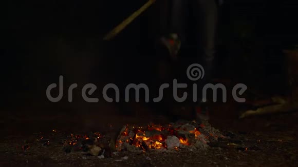 一个男孩在晚上拿着木头和从篝火中散发火花的不规则镜头视频的预览图