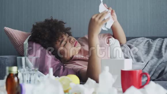 生病的非洲裔美国女孩躺在沙发上用水吃药视频的预览图
