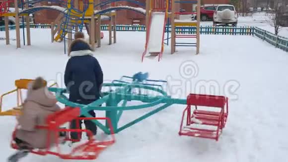 可爱的快乐女孩在冬天玩五颜六色的旋转木马视频的预览图