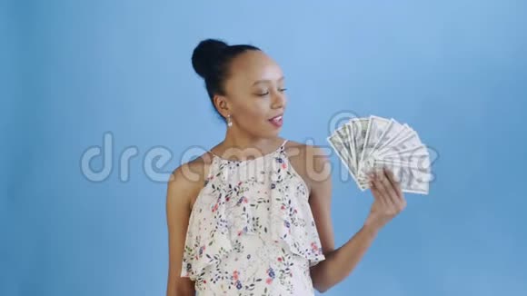 体贴成功的非洲裔美国妇女蓝色背景有钱带花的白色连衣裙视频的预览图