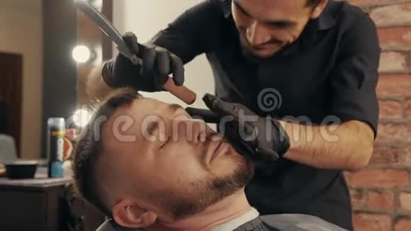 在男式沙龙里用直剃须刀将理发师刮胡子贴在脸上脸上留着剃须刀的头发视频的预览图