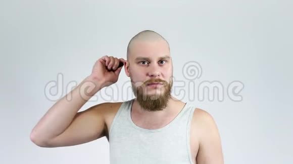 有胡子的秃头年轻人用梳子梳他的秃头哭了视频的预览图