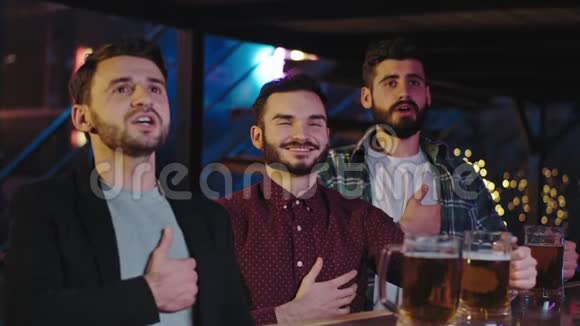 魅力四射的三个人在酒吧里对着镜头唱着他们最喜欢的球队的歌视频的预览图