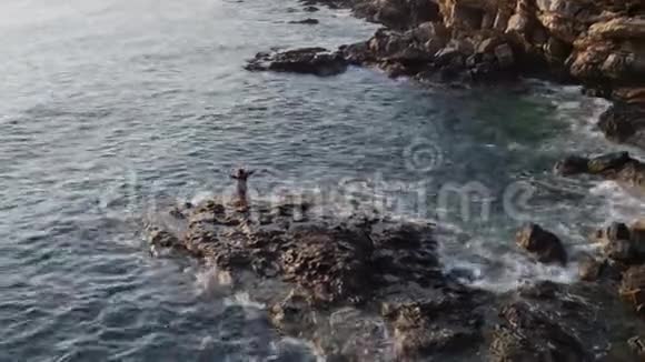在海角悬崖海岸上跳舞的女孩的空中摄影视频的预览图