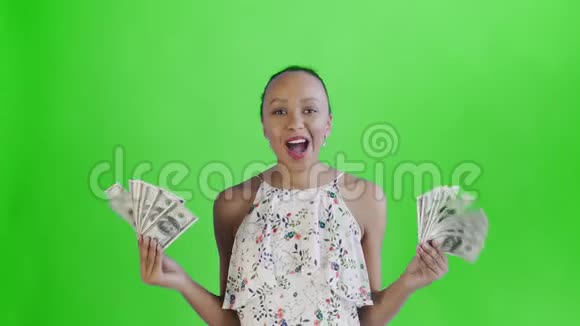 满意高兴兴奋非洲裔美国妇女展示钱说我的上帝在绿色背景白色礼服与视频的预览图