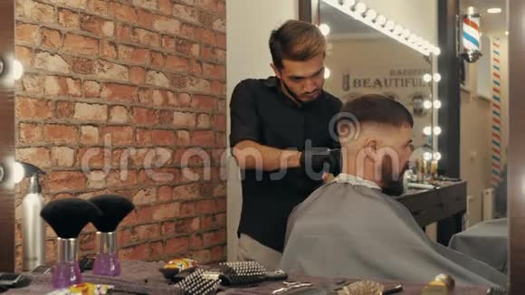 年轻理发师美容男客户镜子里的倒影视频的预览图