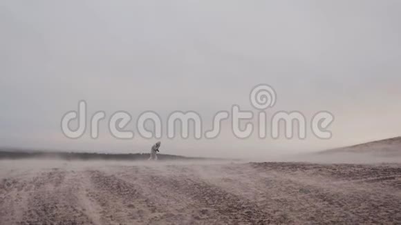在斯堪的纳维亚半岛的冬季沙丘上女性在极端的狂风下艰难地行走背部非常宽阔视频的预览图