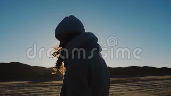 电影拍摄的美丽的背部照明旅游妇女穿着冬天的衣服看相机在风海海岸缓慢的运动视频的预览图