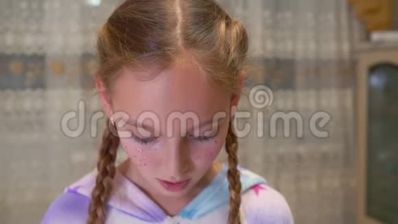 不满意的小女孩在家看相机的特写镜头视频的预览图