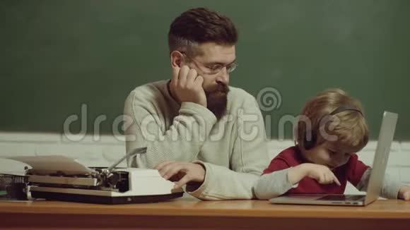 父子俩用旧打字机和笔记本电脑打字老年人和年轻人技术进步视频的预览图