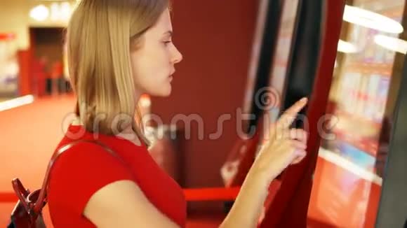 穿红色t恤的年轻美女在电影院的自动售货机买电影票视频的预览图