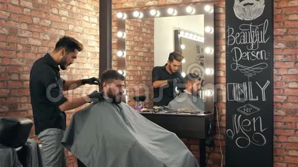 理发店的理发师给微笑的男客户理发视频的预览图