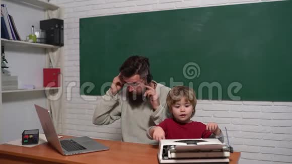 父亲和儿子桌子上有旧打字机和笔记本电脑老年人和年轻人技术进步视频的预览图