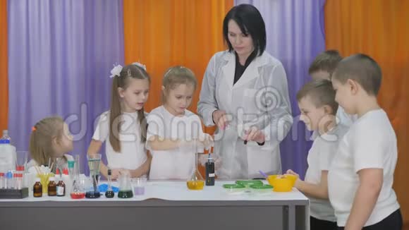 儿童化学实验女孩把蓝色的液体倒入一个带有黄色液体的瓶子里女人摇了摇视频的预览图