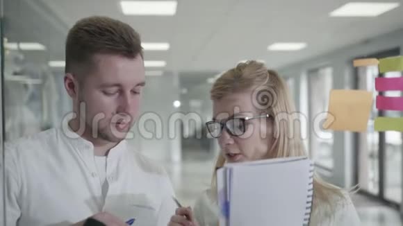 商业计划男人和女人在玻璃白板上使用粘性笔记头脑风暴主管女人与视频的预览图