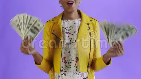 满意快乐兴奋的非洲裔美国妇女在紫色背景上展示金钱和说上帝保佑的肖像视频的预览图