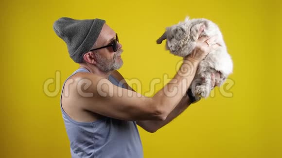 嬉皮士戴着太阳镜的大胡子男人和一只宠物兔子说话视频的预览图