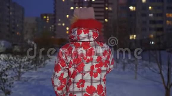 一个戴着冬帽和羽绒服的年轻女孩在冬日的街上走在傍晚的背景里冬日漫步少女视频的预览图