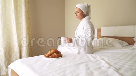 女人用电话在床上喝咖啡视频的预览图