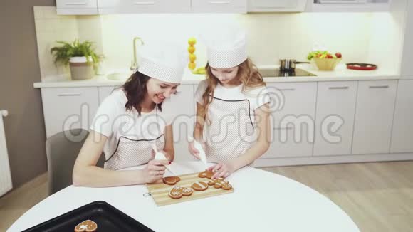 母亲和女儿在家里用釉装饰饼干视频的预览图
