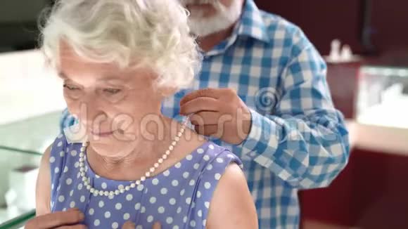幸福的成熟男人帮妻子在商店戴珍珠项链视频的预览图