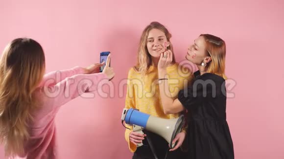 三个年轻的女权主义者女孩的肖像被隔离在粉红色的背景上穿着五颜六色的衬衫视频的预览图