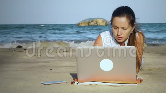 在海滩上使用笔记本电脑的女自由职业者视频的预览图