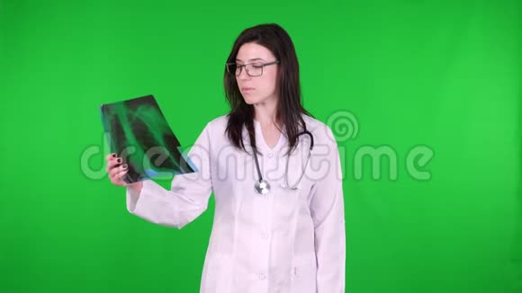 戴眼镜的女医生的肖像穿着白色的医疗制服用听诊器检查X线图像视频的预览图