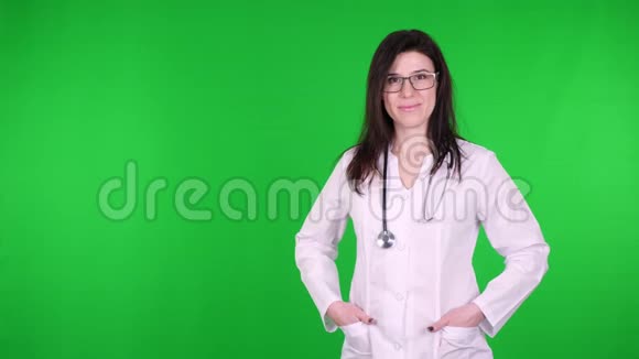 戴着眼镜身穿白色医疗制服和听诊器的年轻快乐女医生的画像视频的预览图