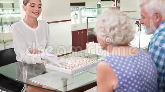 女性珠宝商帮助老年夫妇选择结婚戒指视频的预览图