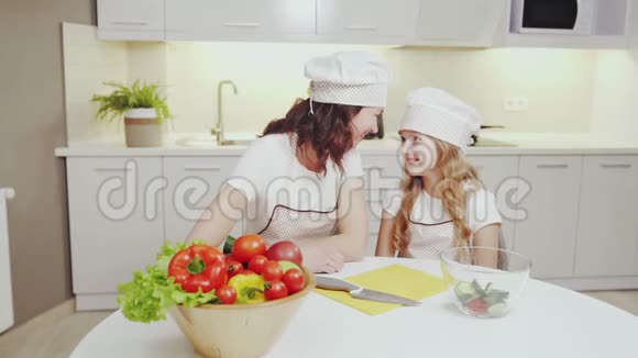 年轻的母亲和她的女儿正在厨房做饭视频的预览图