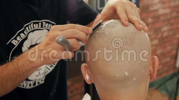 理发店用直剃刀和泡沫的秃头男造型师剃光头把剃须刀贴在里面的光头视频的预览图