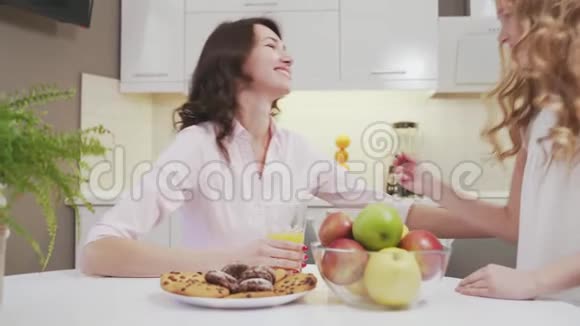小女孩和迷人的女人坐在厨房的桌子上视频的预览图