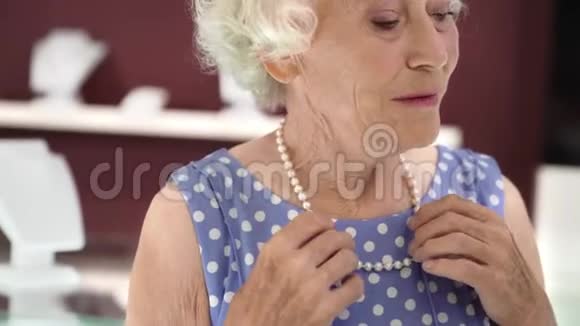 在珠宝店试戴珍珠项链的迷人老太太视频的预览图