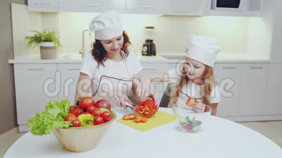 可爱的女孩和她的母亲在厨房里切红辣椒视频的预览图