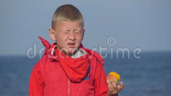 海景穿红色夹克的男孩打喷嚏孩子很高兴吃了一个桃子视频的预览图