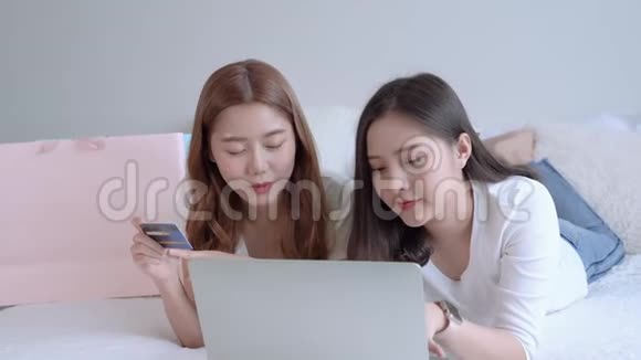 两位亚洲女性正通过床上的笔记本电脑使用网上购物信用卡消费者技术的概念是视频的预览图