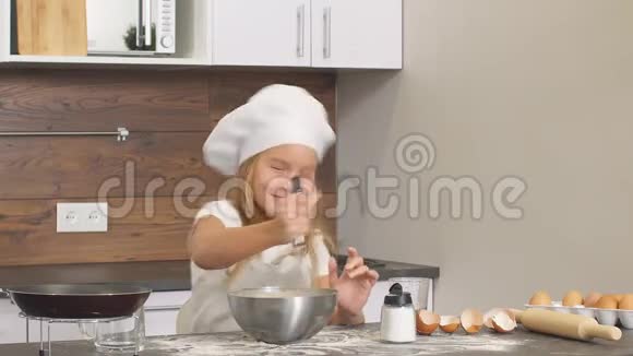 白种人小女孩试着在厨房里独立烘焙把面团混合在碗里视频的预览图