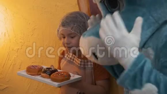 可爱的微笑男孩戴着帽子围裙拿着带甜甜圈的托盘视频的预览图